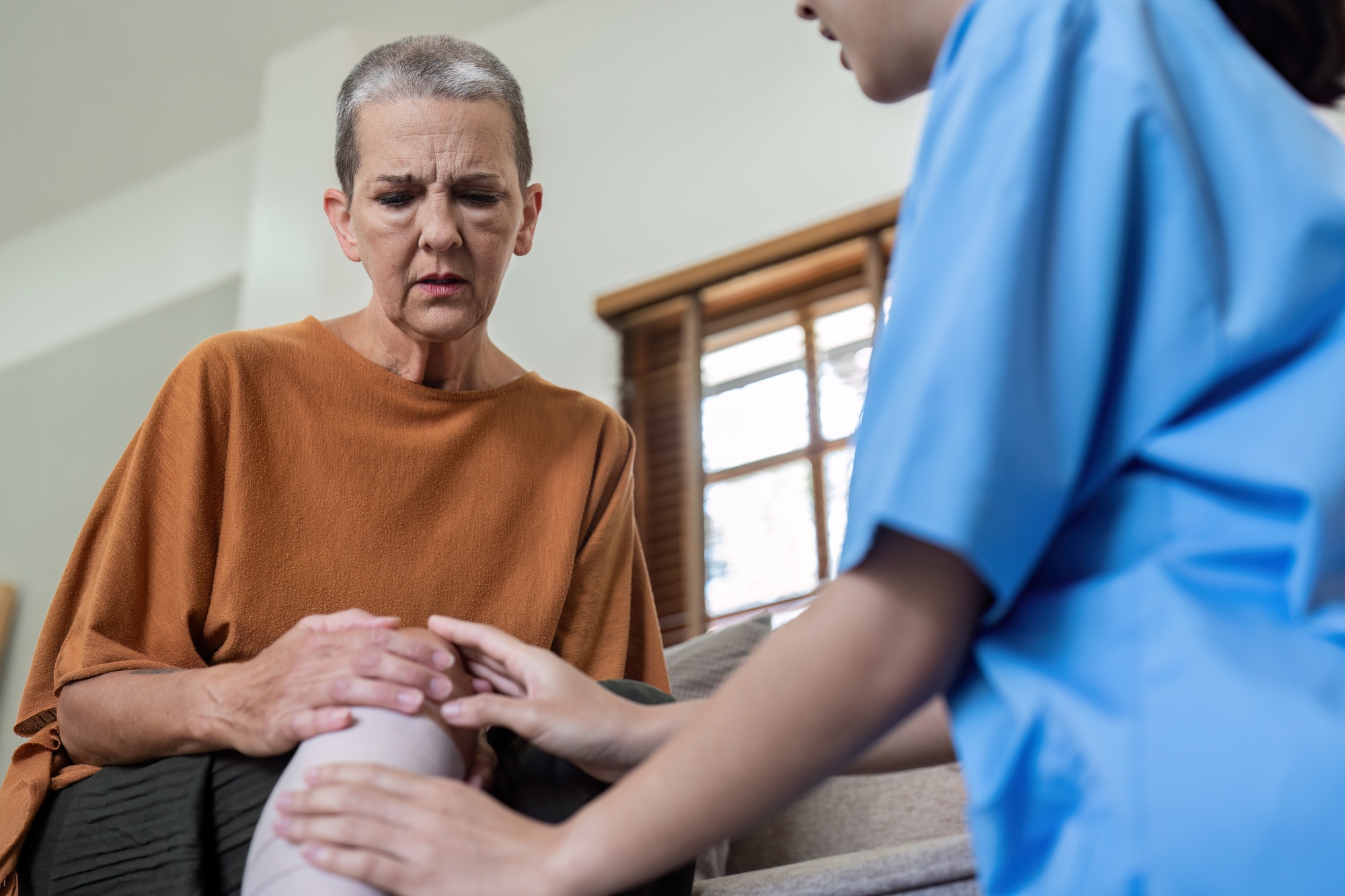 Elderly women have knee pain from osteoarthritis and have their symptoms examine by doctor for